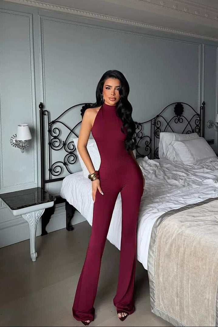 Femme portant une combinaison halter bordeaux dans une chambre chic.
