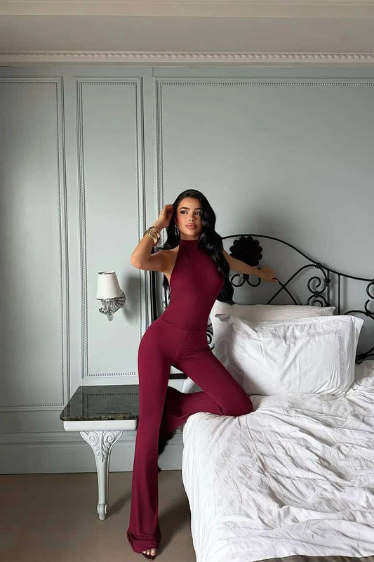 Femme portant une combinaison halter bordeaux dans une chambre chic.