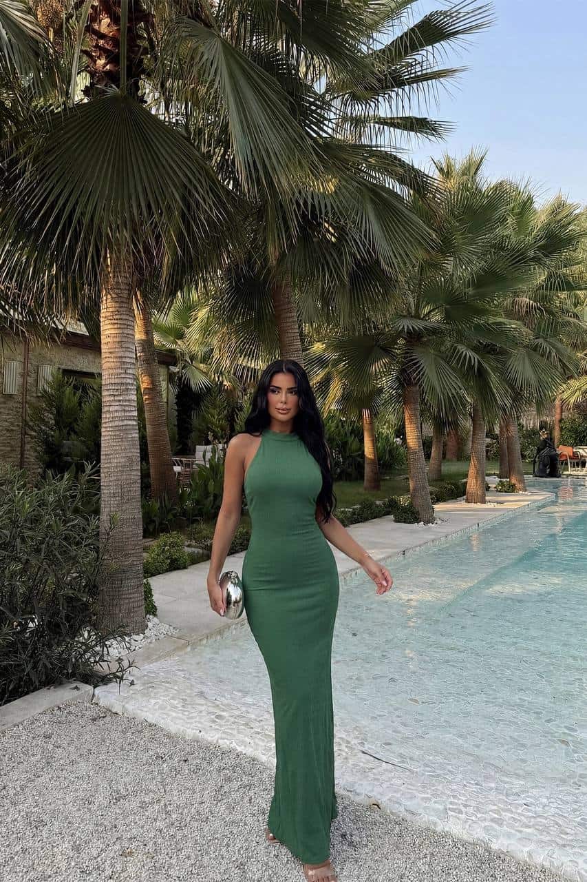 Femme portant une robe longue halter vert sauge près de la piscine.
